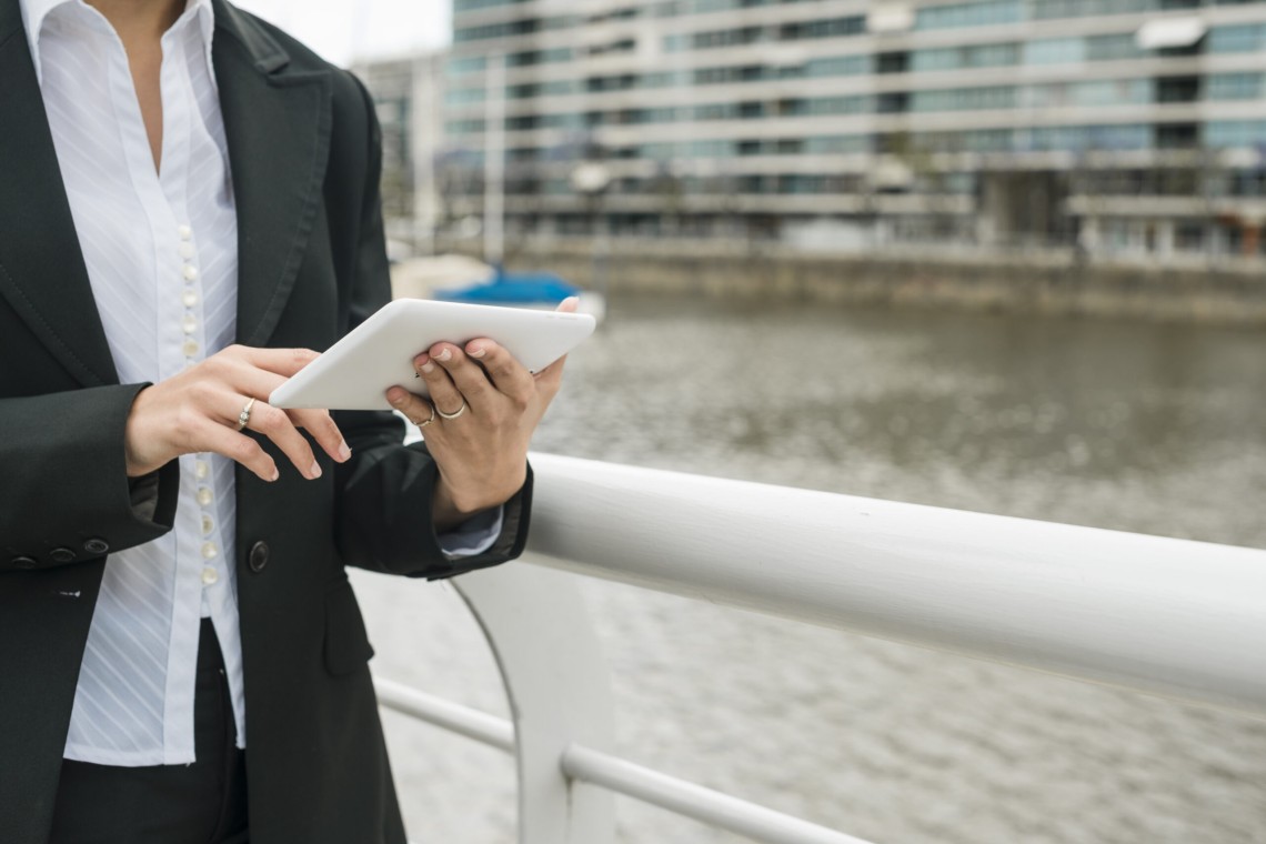 mid-section-young-woman-standing-near-harbor-using-mobile-phone