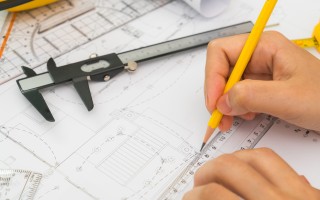 Hand over Construction plans with yellow helmet and drawing tool