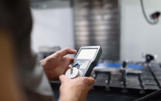 Worker entering data in CNC machine at factory floor to get the